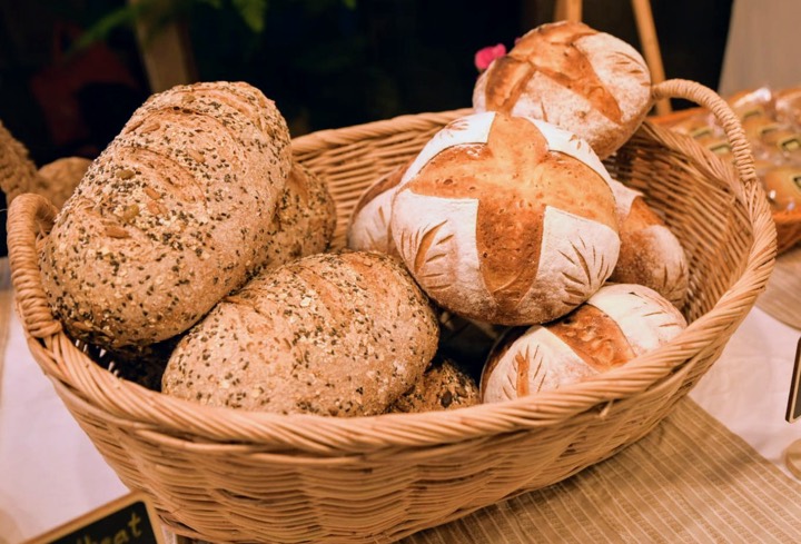 A wicker basket of seeded and scored sourdough loaves on the café counter