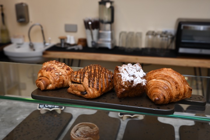 Butter croissant, pain au chocolat and sugar-dusted pastries on a slate board in the café counter