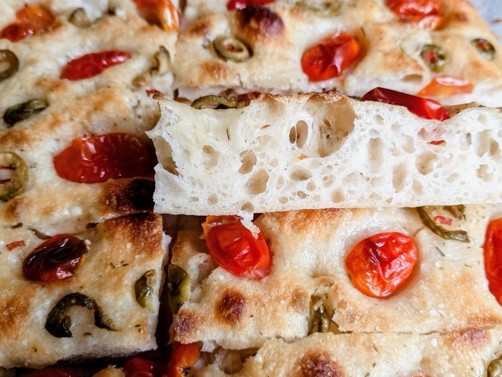 Close-up of airy focaccia slices topped with cherry tomatoes and olives